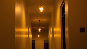 Um corredor estreito com um luminária no teto e uma porta no final.