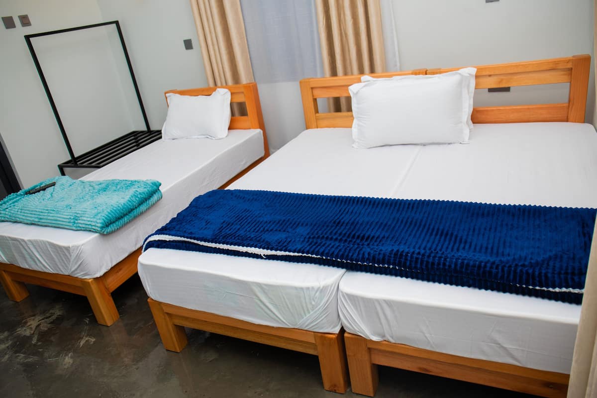 Two single beds with wooden frames, white bedding, and a blue blanket on one bed.