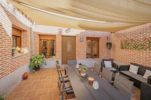 Un patio con pared de ladrillo, una mesa, sillas y un sofá.
