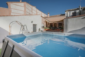 An outdoor swimming pool with a clear view of the surrounding buildings and a ladder leading to a door.