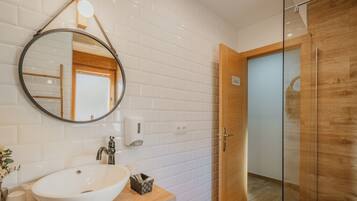 Une salle de bain avec un lavabo blanc, un miroir et un meuble-lavabo en bois.