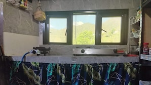 Una cocina con ventana, estufa a gas y dispensador de agua.