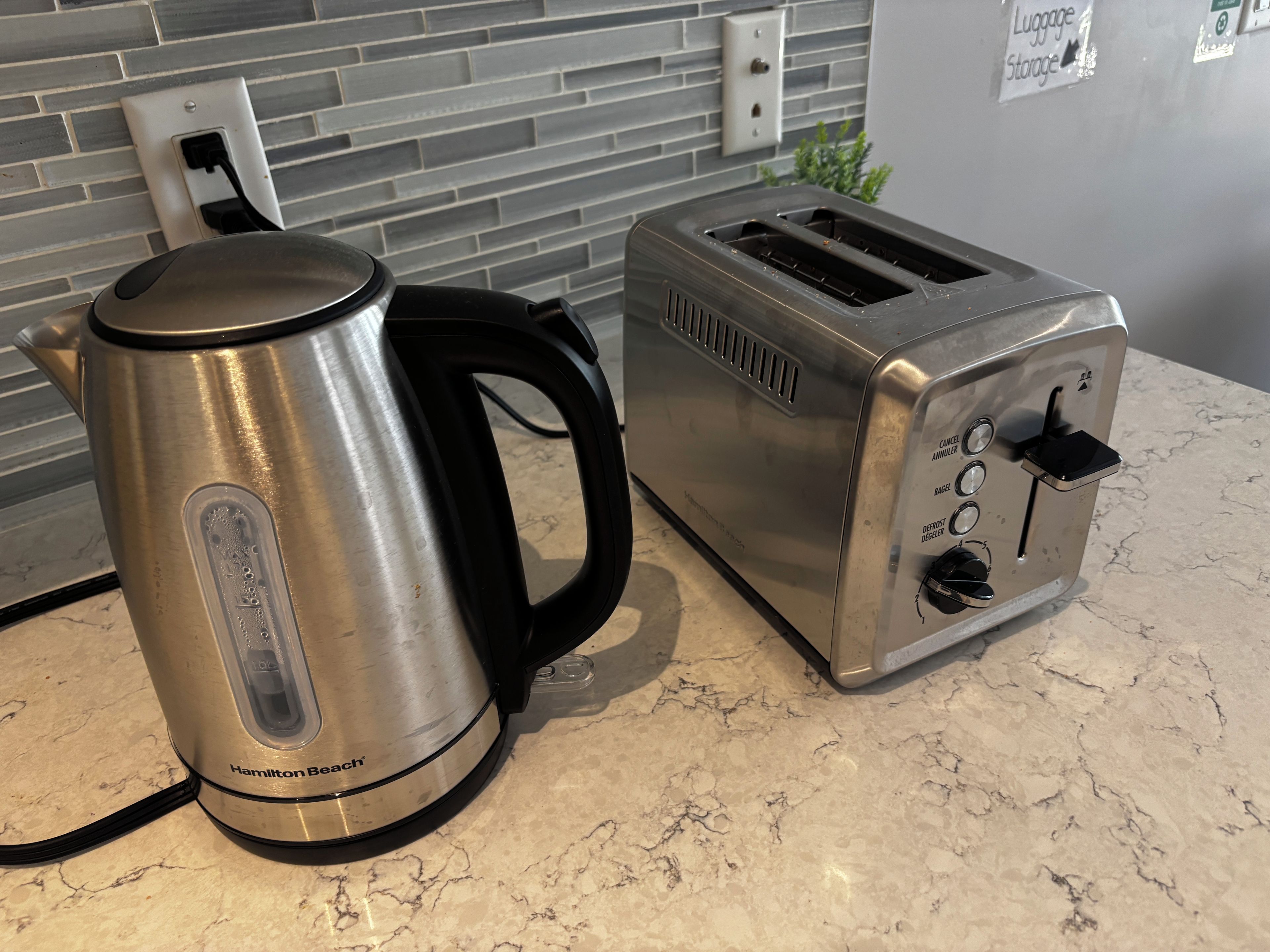 Una cocina con una tetera eléctrica Hamilton Beach y un tostador sobre una encimera de mármol.