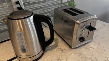 Una cocina con una tetera eléctrica Hamilton Beach y un tostador sobre una encimera de mármol.