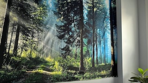 Un dormitorio con un mural grande de temática forestal, una cama y una planta en maceta.