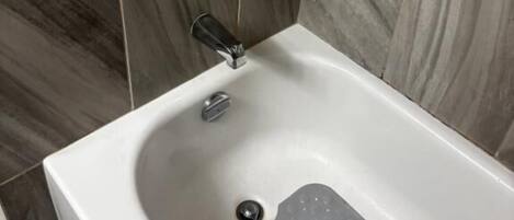 A bathroom with a bathtub, a showerhead, and a faucet.
