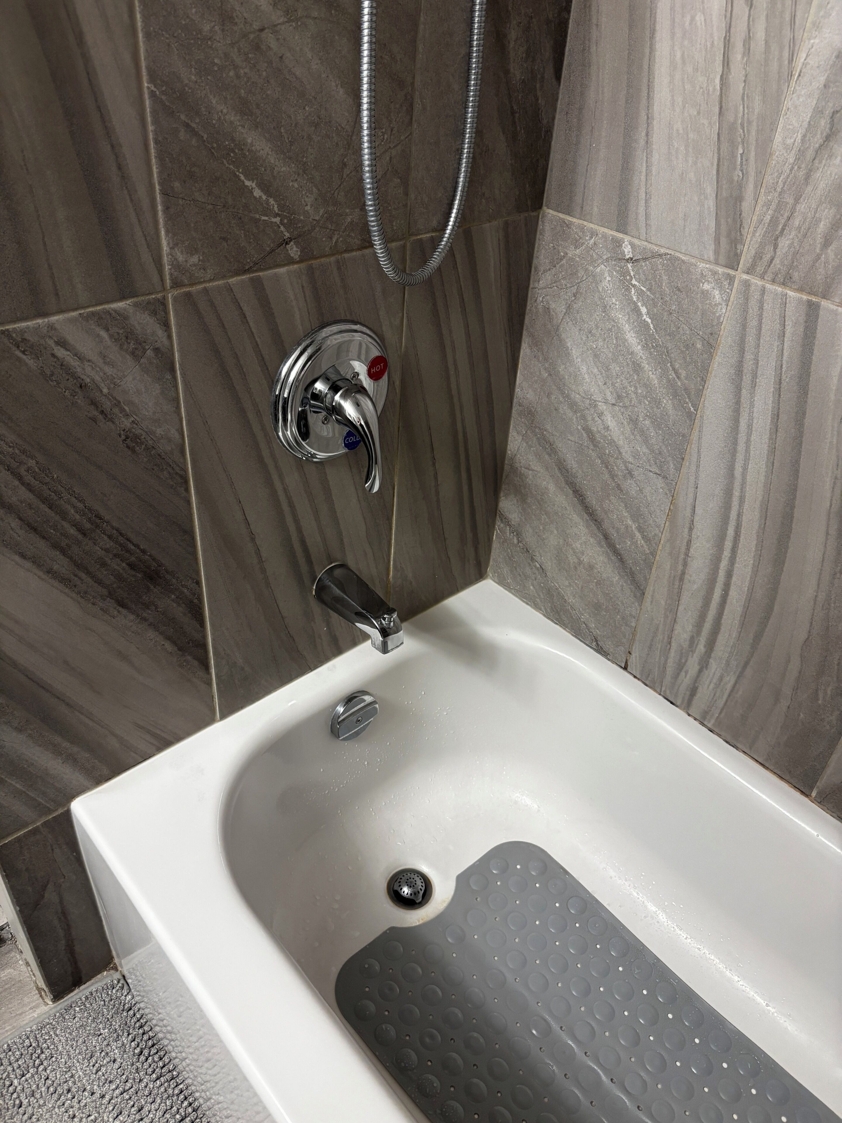 Un baño con bañera, ducha y grifo con mandos para agua caliente y fría.