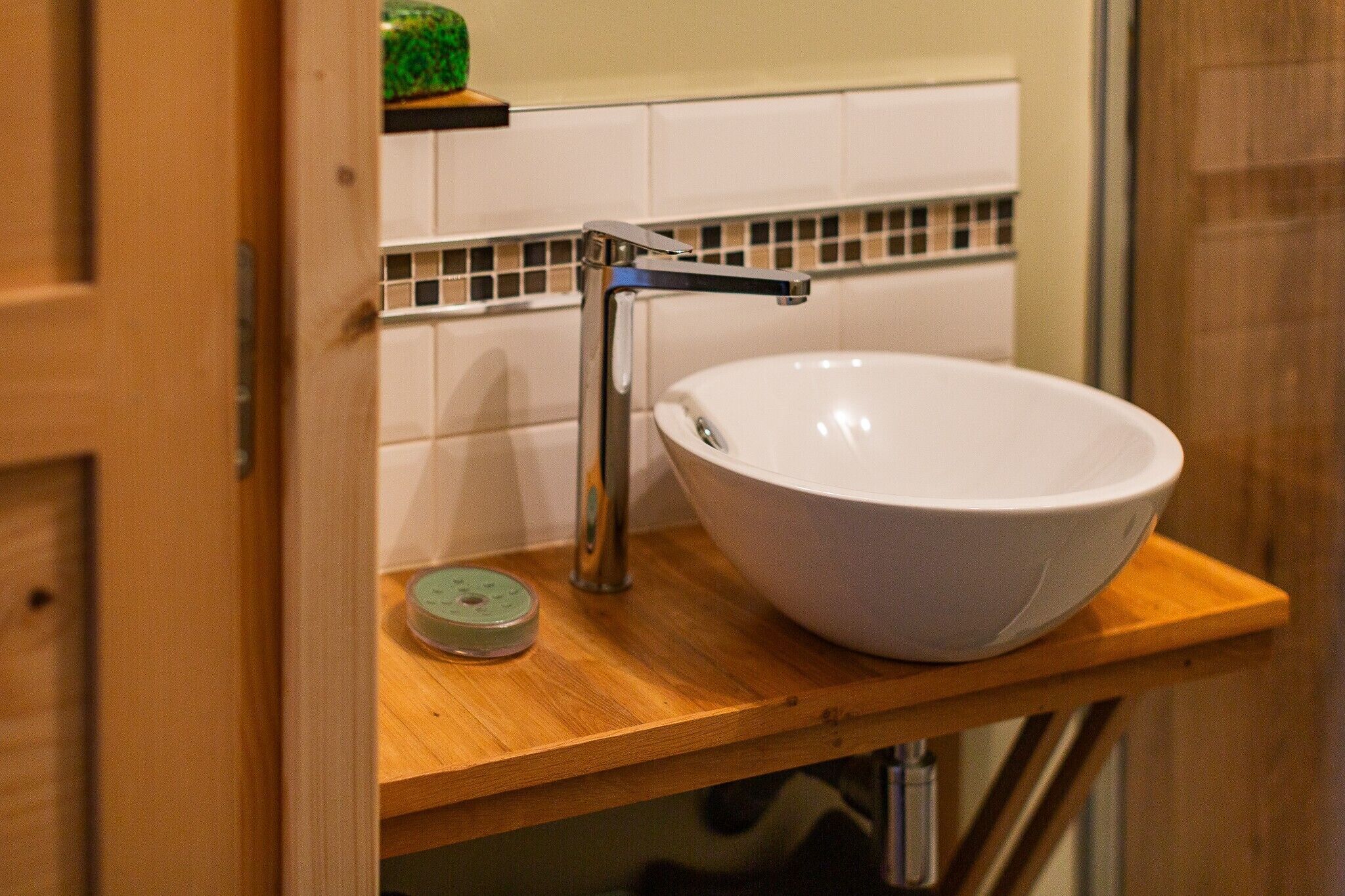 Un bagno con un lavabo a incasso bianco, un rubinetto cromato e un piano d'appoggio in legno.