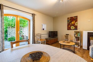 Una sala de estar acogedora con televisión, chimenea, comedor con mesa y sillas, y vista a zonas verdes.