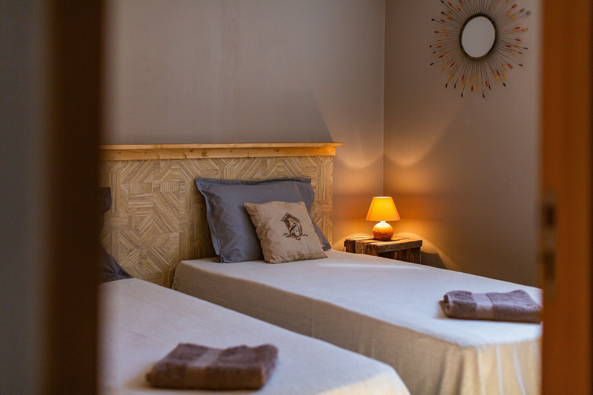 Une chambre d ’hôtel avec deux lits, une table de chevet avec une lampe et un élément décoratif mural.