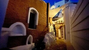A narrow alleyway with a brick building on the left and a white building on the right.