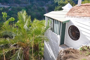 Un edificio blanco con puerta verde, ventana redonda y techo blanco.