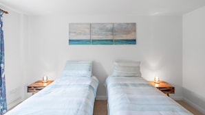A bedroom with two beds, a wall-mounted painting, bedside lamps, and a ceiling light. - Dairy Close Parking By My Getaways (Uckfield)