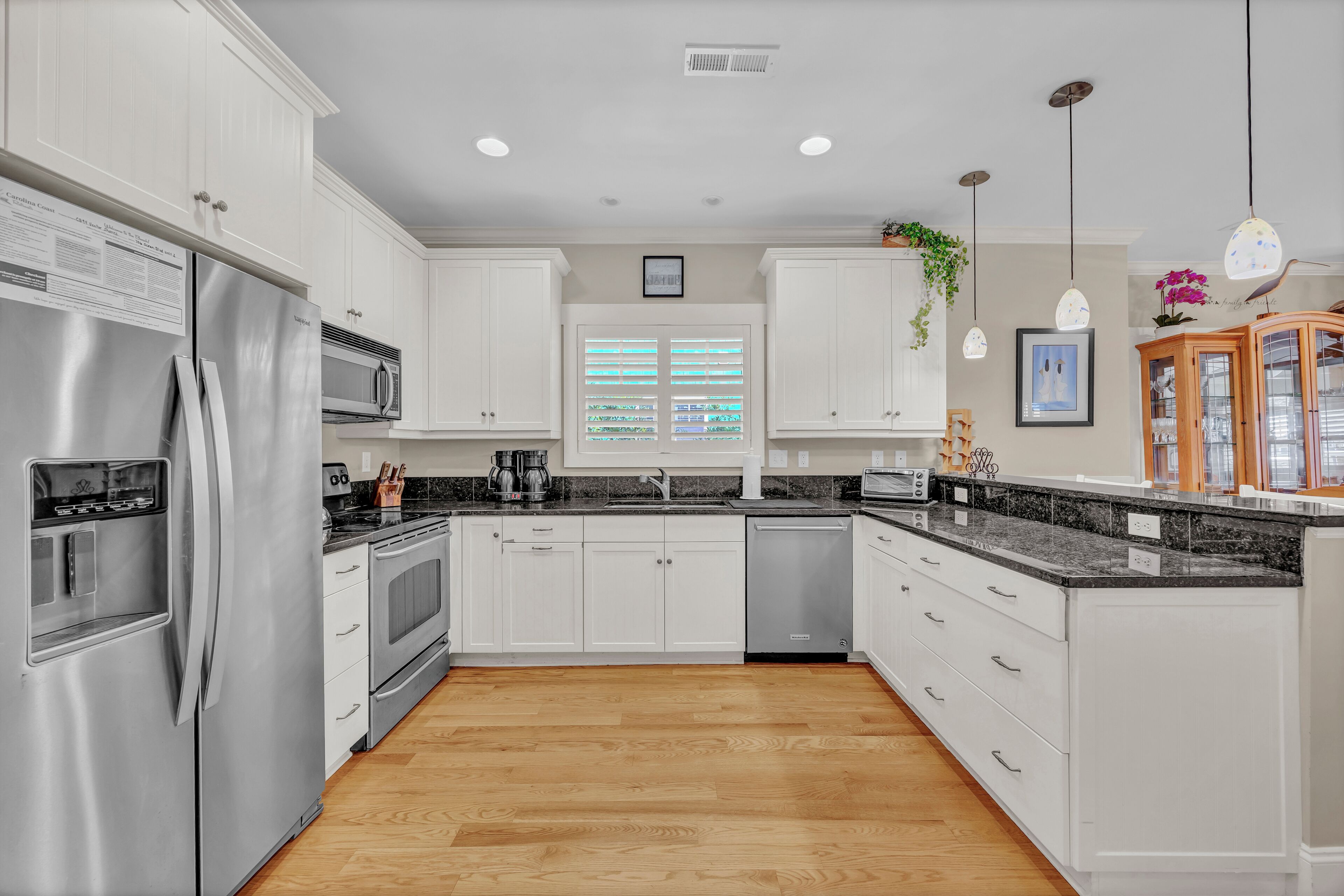 A modern kitchen with white cabinets, stainless steel appliances, and a granite countertop.