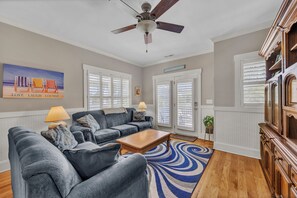Ein Wohnzimmer mit einer Sofagarnitur, einem Couchtisch, einem Deckenventilator und einem Bild an der Wand.