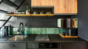 A modern kitchen with a black countertop, wooden cabinets, a microwave, and a coffee machine. - Marina Haven Sea Views Parking By My Getaways (Brighton)