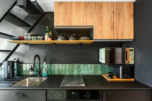 A modern kitchen with a black countertop, wooden cabinets, a microwave, and a coffee machine. - Marina Haven Sea Views Parking By My Getaways (Brighton)