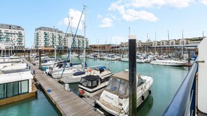 A marina with boats docked, a wooden pier, and buildings in the background. - Marina Haven Sea Views Parking By My Getaways (Brighton)