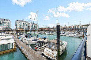 A marina with boats docked, a wooden pier, and buildings in the background. - Marina Haven Sea Views Parking By My Getaways (Brighton)