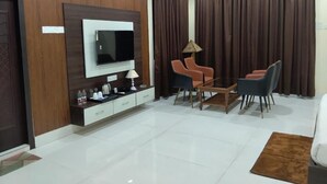 A modern living room with a flat-screen TV, a coffee table, two chairs, a sofa, and a ceiling fan. - The Pride Gitbitan (Asansol)