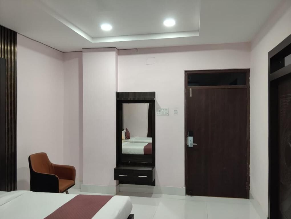 A hotel room with a bed, a chair, a wardrobe, a door, and a mirror.