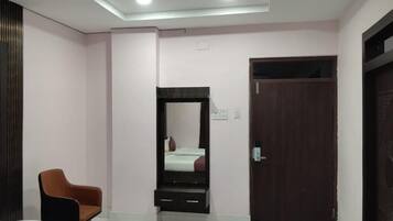 Une chambre d’hôtel avec un lit, une chaise, une armoire, une porte et un miroir.