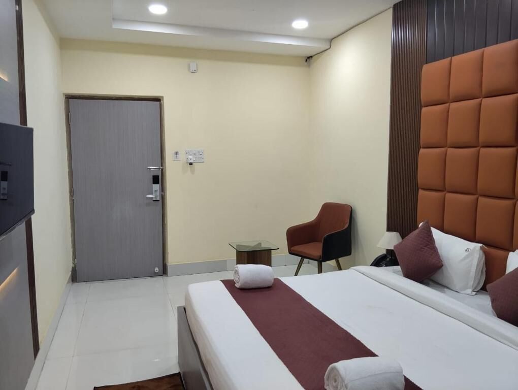 A hotel room with a bed, a chair, a small table, and a door.