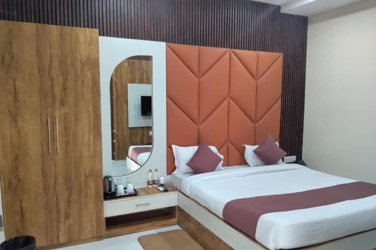 Un dormitorio con cama, armario de madera, espejo y mesita de noche con artículos de aseo.