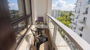 Ein Balkon mit Tisch und Stühlen, einem Blumentopf und einem gerahmten Schild.