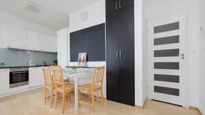 Eine moderne Küche mit weißen Schränken, einem schwarzen Kühlschrank und einem Esstisch mit Stühlen.