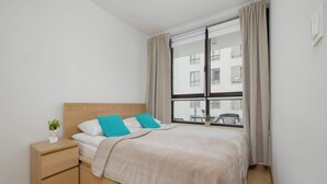 Ein ordentlich eingerichtetes Schlafzimmer mit Bett, Nachttisch und einem Fenster mit Vorhängen.