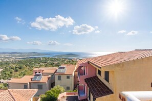 Eine Küstenwohngegend mit terrakottafarbenen Dächern, blauem Himmel und Blick auf das Meer.
