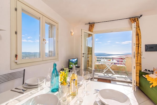A dining area with a table set for two, a television, and a view of the landscape. - Elicriso (Tempio Pausania)