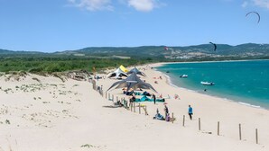Una playa con tiendas de campaña, una cerca y cielo despejado.