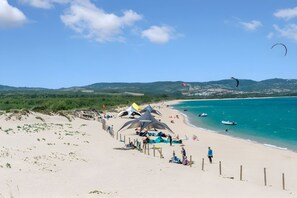 Ein Strand mit Zelten, einem Zaun und blauem Himmel.