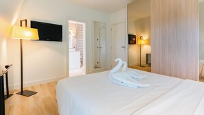 A hotel room with a bed, a flat-screen TV, a lamp, a mirror, and a wardrobe. - Le Belvédère - Penthouse, sea & country view (Tourgéville)