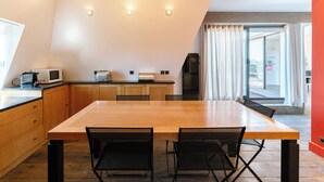 A modern kitchen with a wooden table and chairs, a microwave, and a refrigerator. - Le Belvédère - Penthouse, sea & country view (Tourgéville)