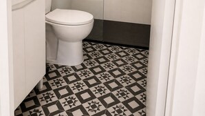 Et badeværelse med toilet, bruser og vask.