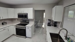 A kitchen with white cabinets, a microwave, an oven, a dishwasher, and a sink.