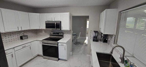 A kitchen with white cabinets, a microwave, an oven, a dishwasher, and a sink.