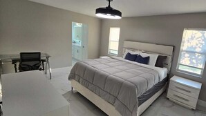 A bedroom with a bed, bedside tables, a desk, and a chair.