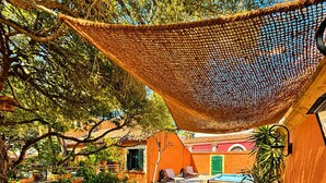 Eine Terrasse im Freien mit Holzmöbeln, einer Hängematte und einem Pool im Hintergrund.