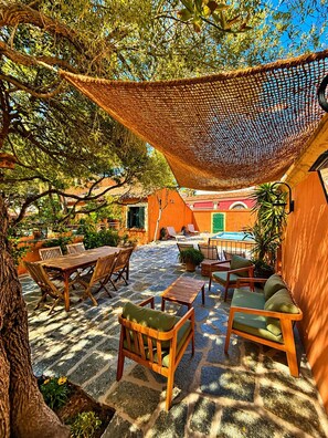 An outdoor patio with wooden furniture, a hammock, and a pool in the background. - VILLA ANTONIA Charming house with heated pool - Calvi town center. (Calvi)