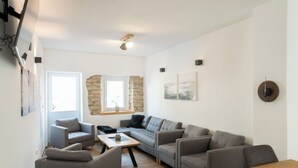 A modern living room with a sofa set, a coffee table, and a wooden dining table. - Wonderful private villa for 10 guests with TV and terrace (Rittersdorf)