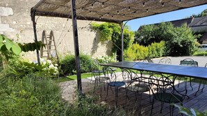 A patio with a table and chairs, surrounded by greenery and a stone wall. - Charming Holiday Home 'Les Griottes Gîte de Charme' with Indoor Pool (Verdigny)