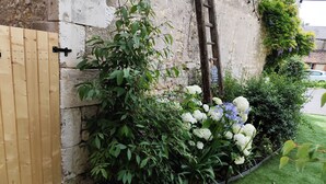 A wooden gate, a stone wall, and a garden with various plants and flowers. - Charming Holiday Home 'Les Griottes Gîte de Charme' with Indoor Pool (Verdigny)
