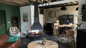 A modern living room with a fireplace, a dining area, and a kitchen. - Charming Holiday Home 'Les Griottes Gîte de Charme' with Indoor Pool (Verdigny)