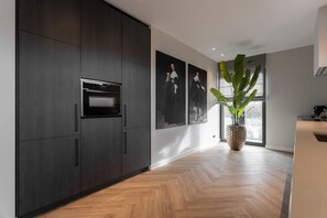 Eine moderne Küche mit dunklen Schränken, einem eingebauten Ofen und einem großen Fenster mit Blick.