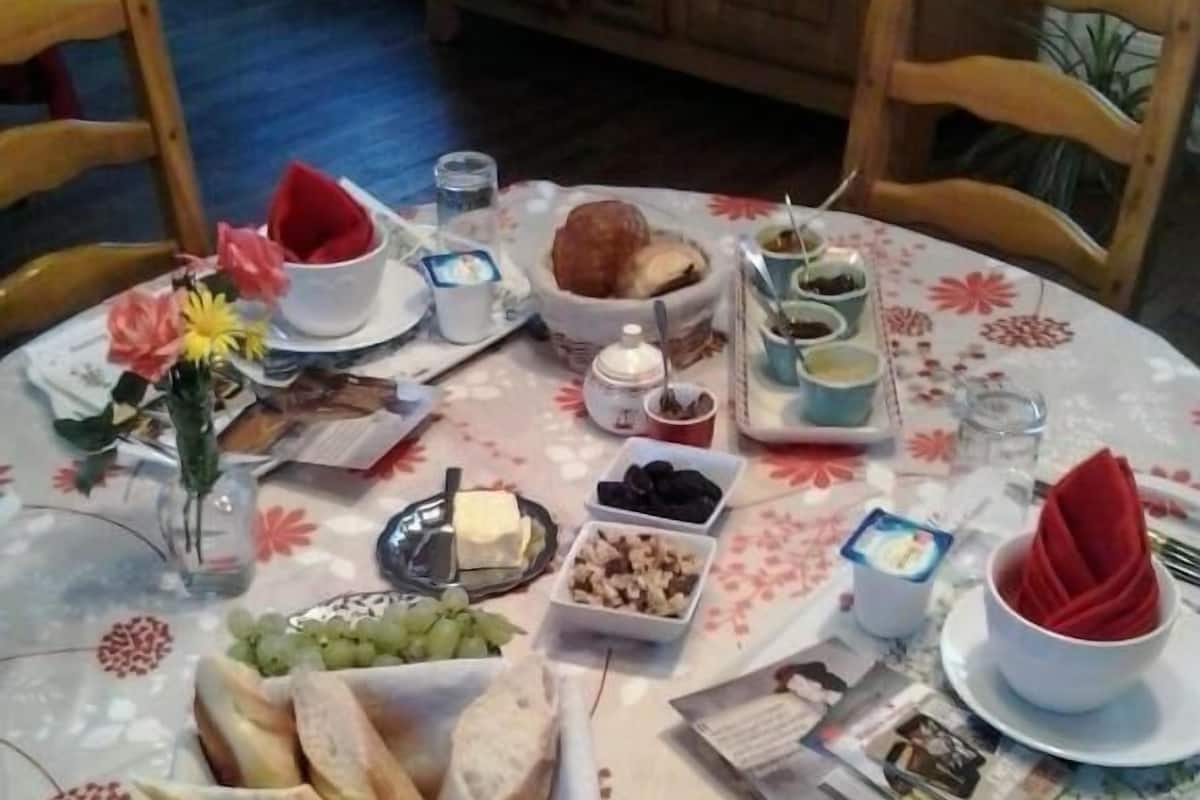 A round dining table with a floral tablecloth, various food items, and a newspaper.