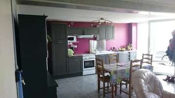 Una cocina con armarios grises, microondas, estufa y mesa de comedor con sillas.